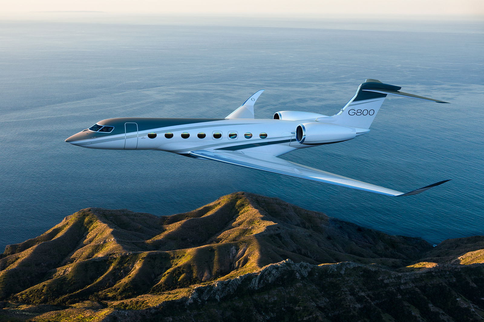 Gulfstream G800 in flight over coastal landscape — ultra-long-range private jet with 8,200 nm range